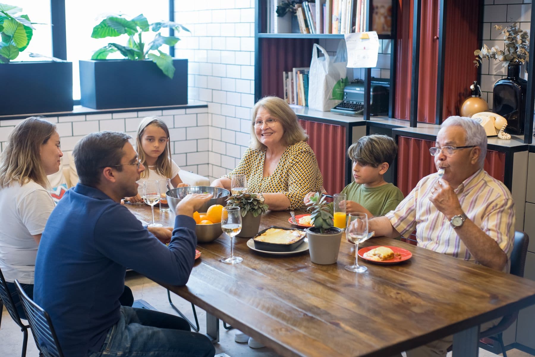 Three generations at one dinner table: grandparents, parents and two children sharing a meal