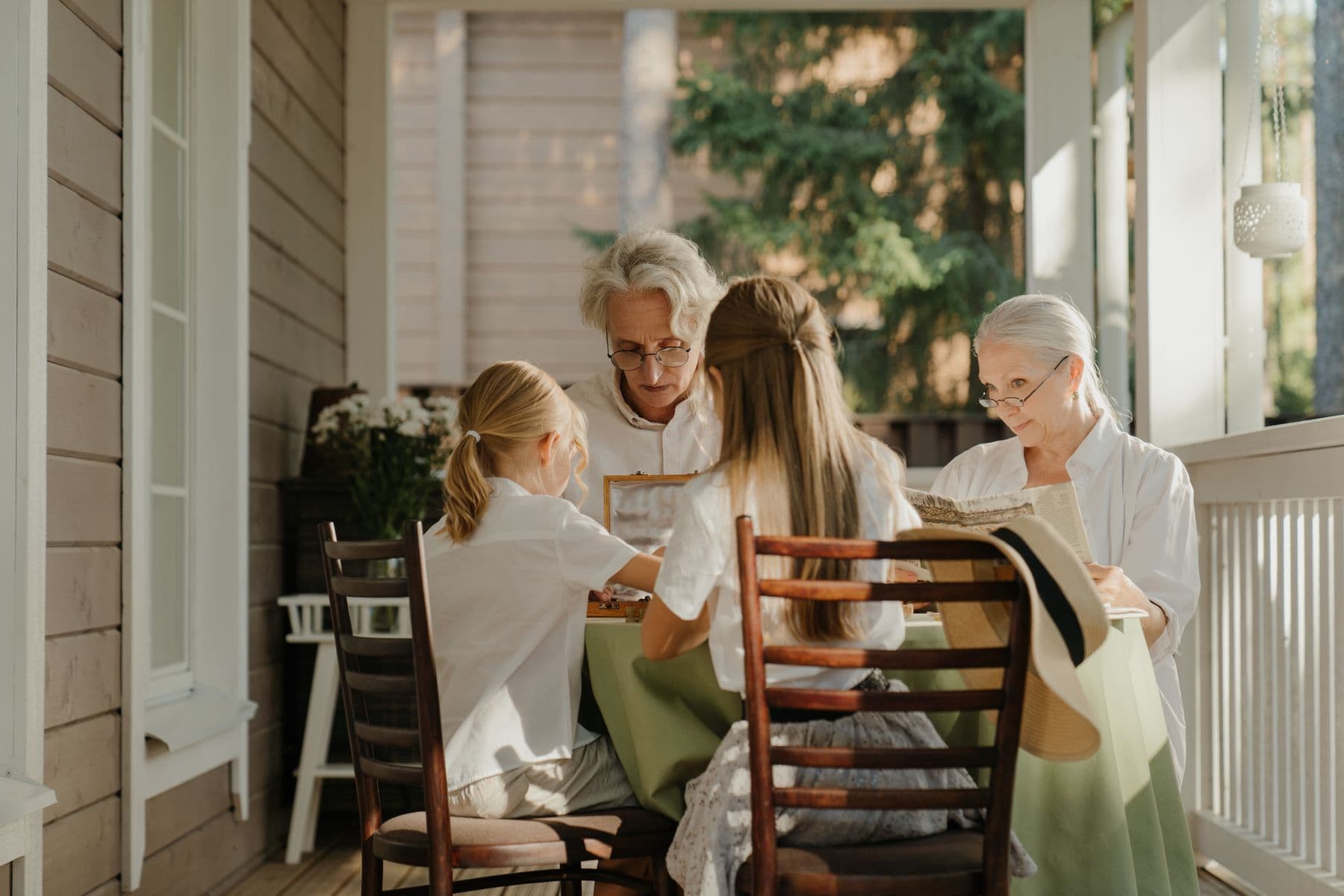 A family of three generations around a table on a sunlit veranda