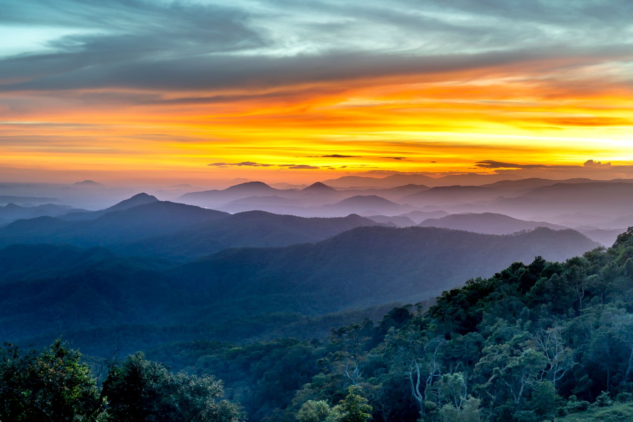 Layered mountain ridges receding into haze under a golden sky