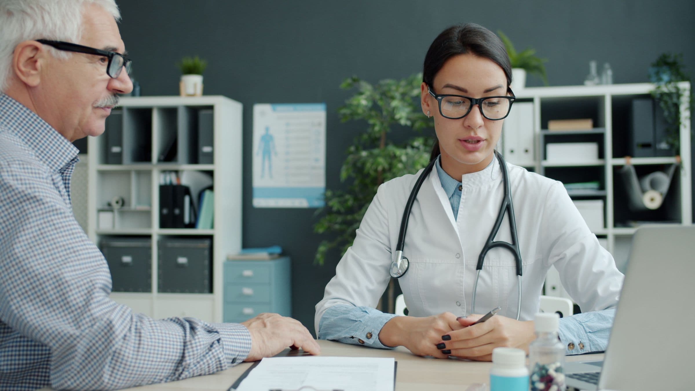 A clinician talking with an older man across a desk